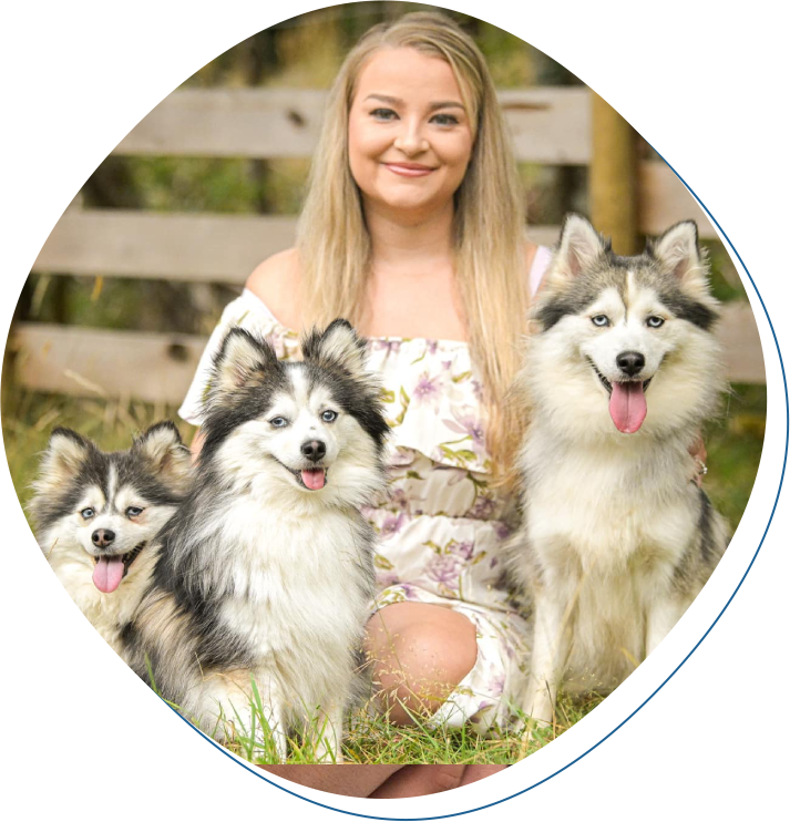 A woman sitting in the grass with two dogs.